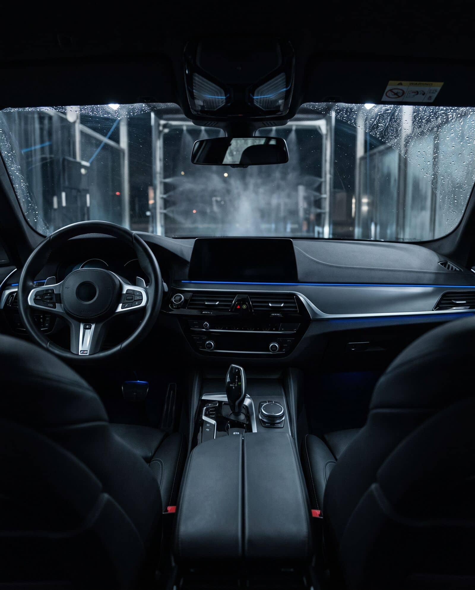 Interior limpo de um carro, com painel e volante pretos e uma linha de luz azul